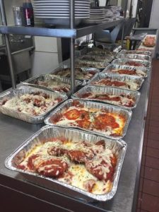 Trays of lasagna are lined up in a kitchen.